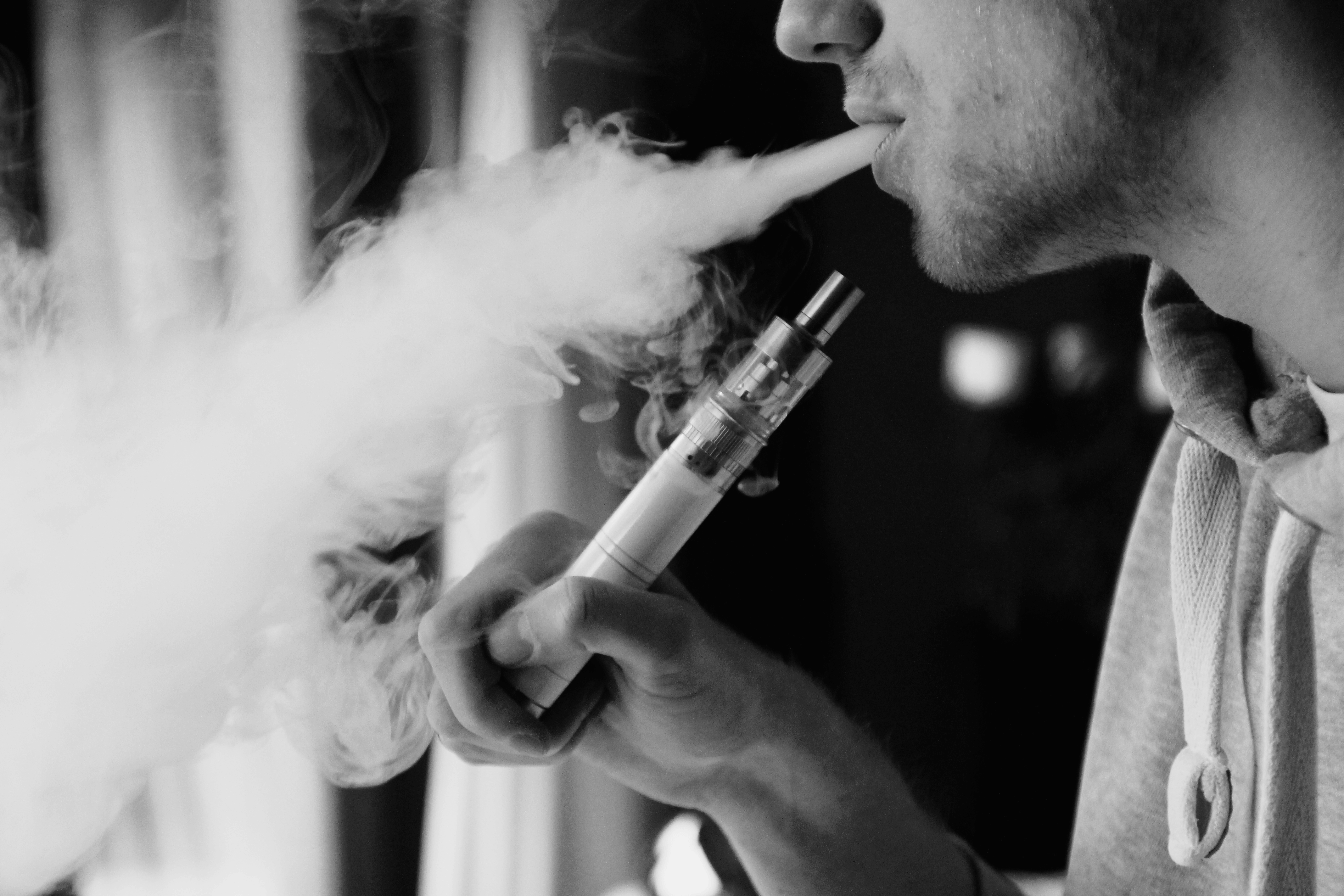 A picture of a young man smoking an e-cigarette.