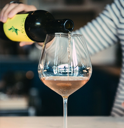 An image of a women pouring wine into a wine glass.